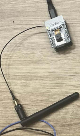 The ESP32-CAM module wired to an external antenna, photographed on a wooden desk